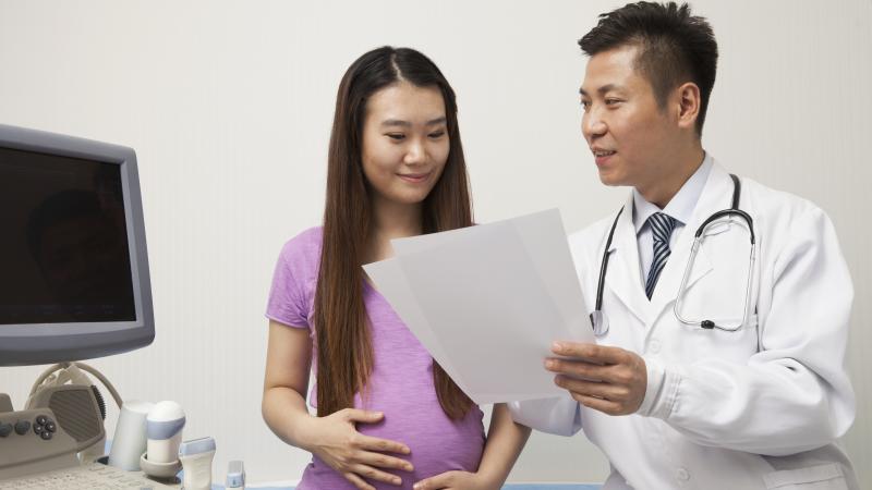 Doctor sharing printed documents with pregnant woman