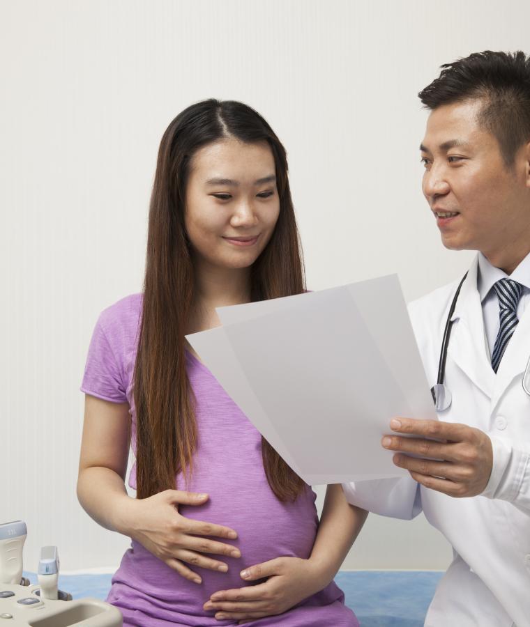 Doctor sharing printed documents with pregnant woman